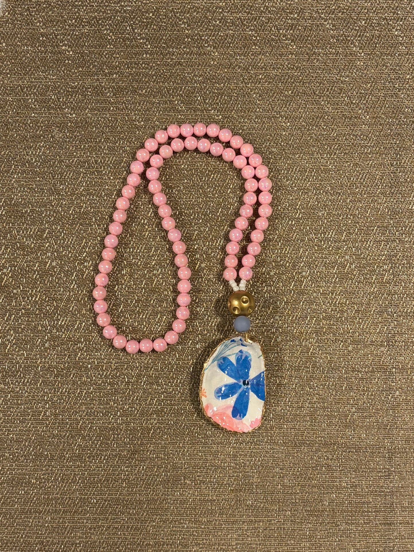 Pink beaded necklace with a decorative oyster shell pendant