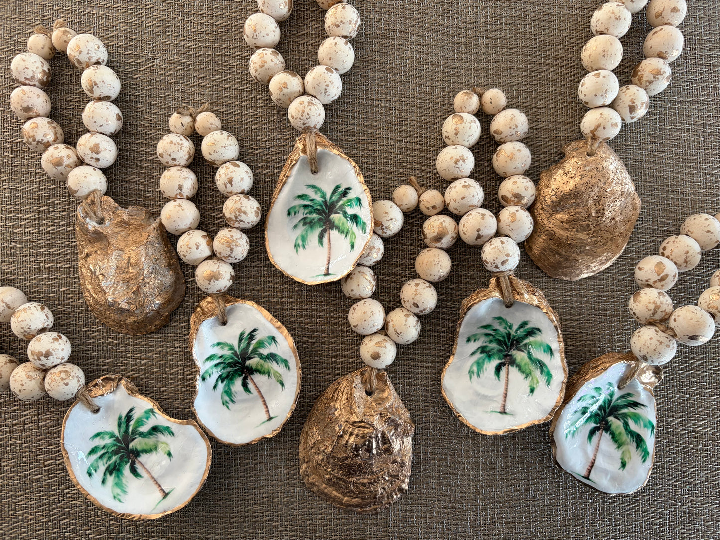 Group of oyster shell wine bottle charms or napkin rings featuring a palm tree.